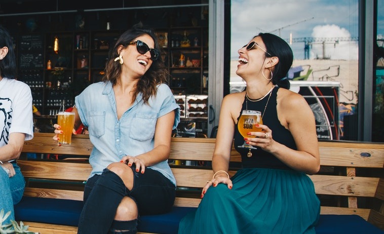 Photo of two women laughing over drinks