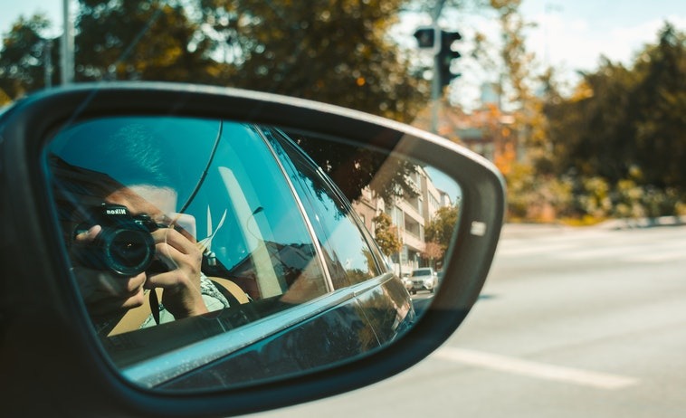 Photo of a car side mirror of a man taking a photo
