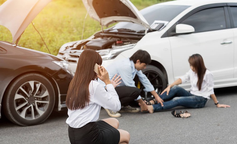 Photo of a breakdown, women on the phone, and man helping a women with her hurt ankle
