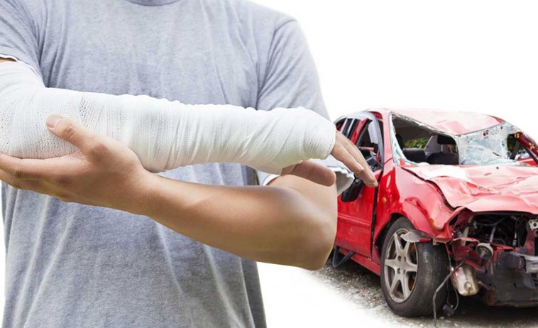 Photo of a man with a hurt arm and crashed car int he background 
