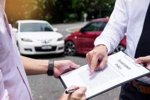 insurance adjuster hands claim form to car accident victim
